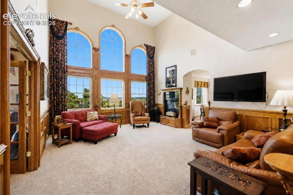 Image 13 of 49: Vaulted ceiling with a ceiling fan, three arched windows, wood paneling, re