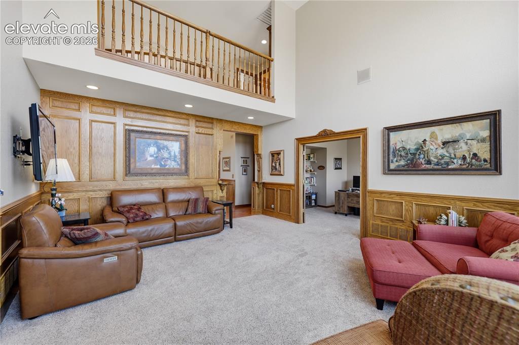 Image 14 of 49: Expansive great room featuring soaring ceilings with an upper-level mezzani