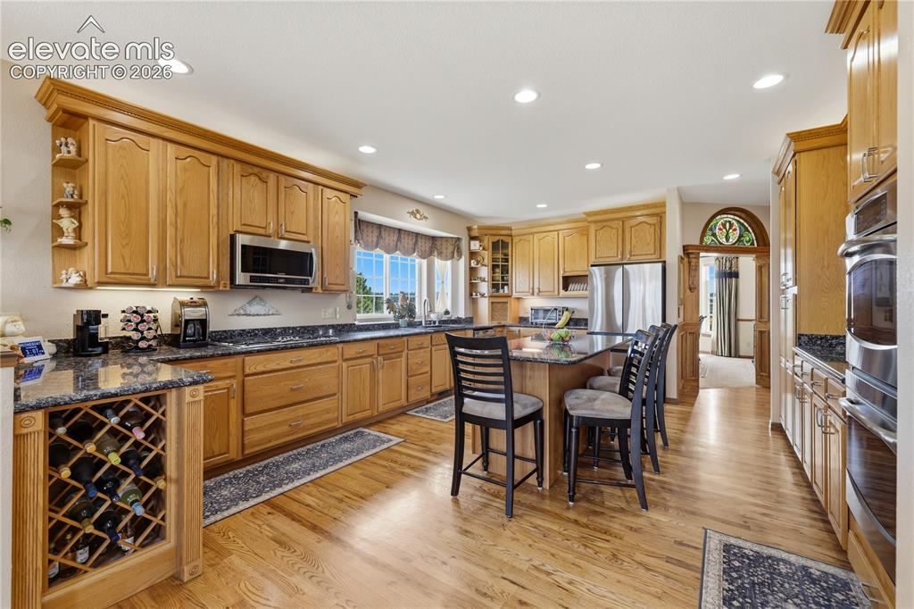 Image 18 of 49: Kitchen featuring wood cabinetry, dark countertops, wood-finish flooring, b