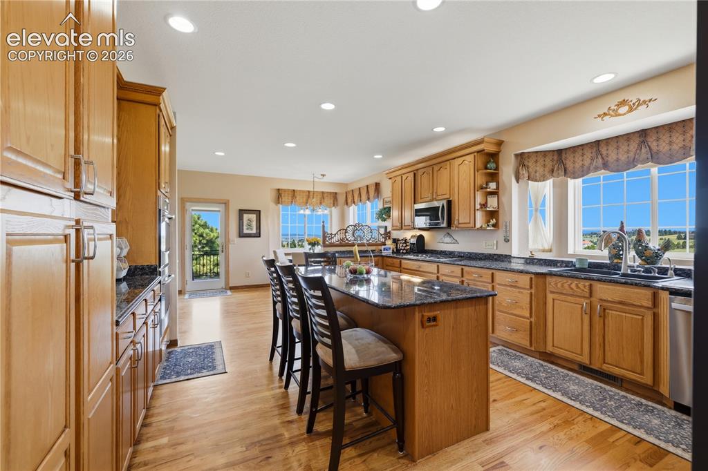 Image 19 of 49: Kitchen featuring wood cabinetry, dark countertops, wood-finish flooring, r