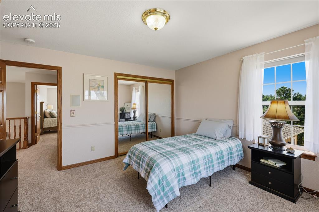 Image 28 of 49: Upstairs Bedroom - Plush carpeting, wood-trim doorways, window with outdoor