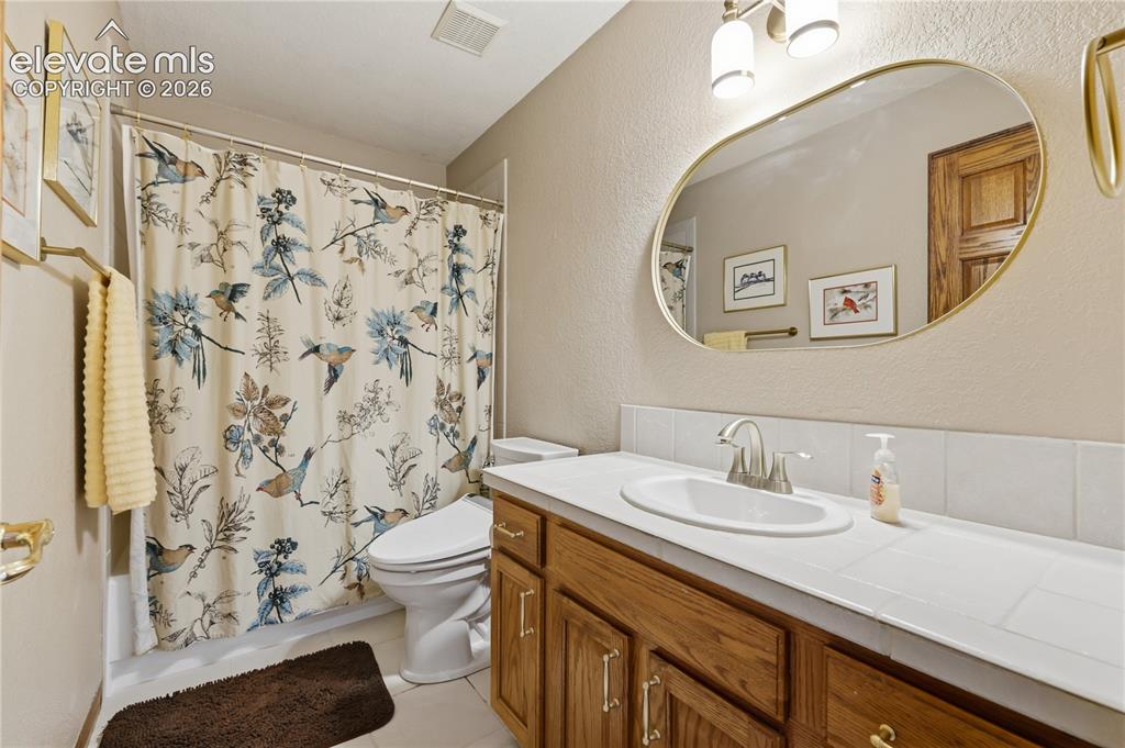 Image 29 of 49: Upstairs Bathroom featuring a wood-finish vanity with a tile countertop, an