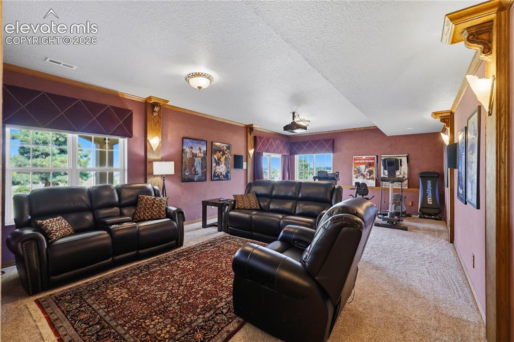 Image 31 of 49: Spacious living room showcasing multiple seating areas with black leather r