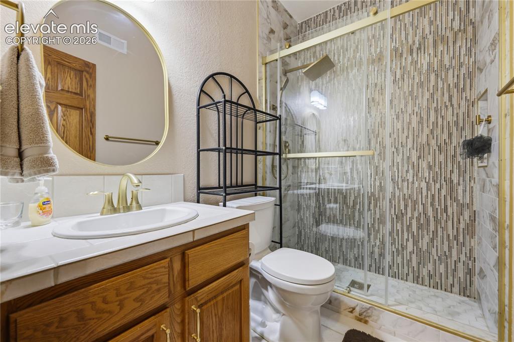 Image 38 of 49: Bathroom featuring a glass-enclosed shower with vertical tile work, a wood 