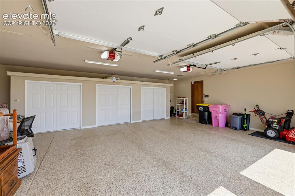Image 40 of 49: Spacious garage featuring epoxy-coated concrete flooring, three white panel