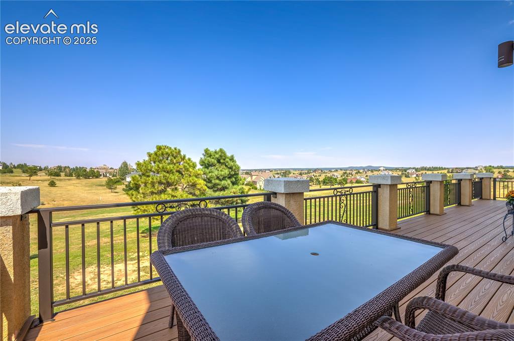 Image 42 of 49: Expansive composite deck with black metal railing overlooking manicured gro