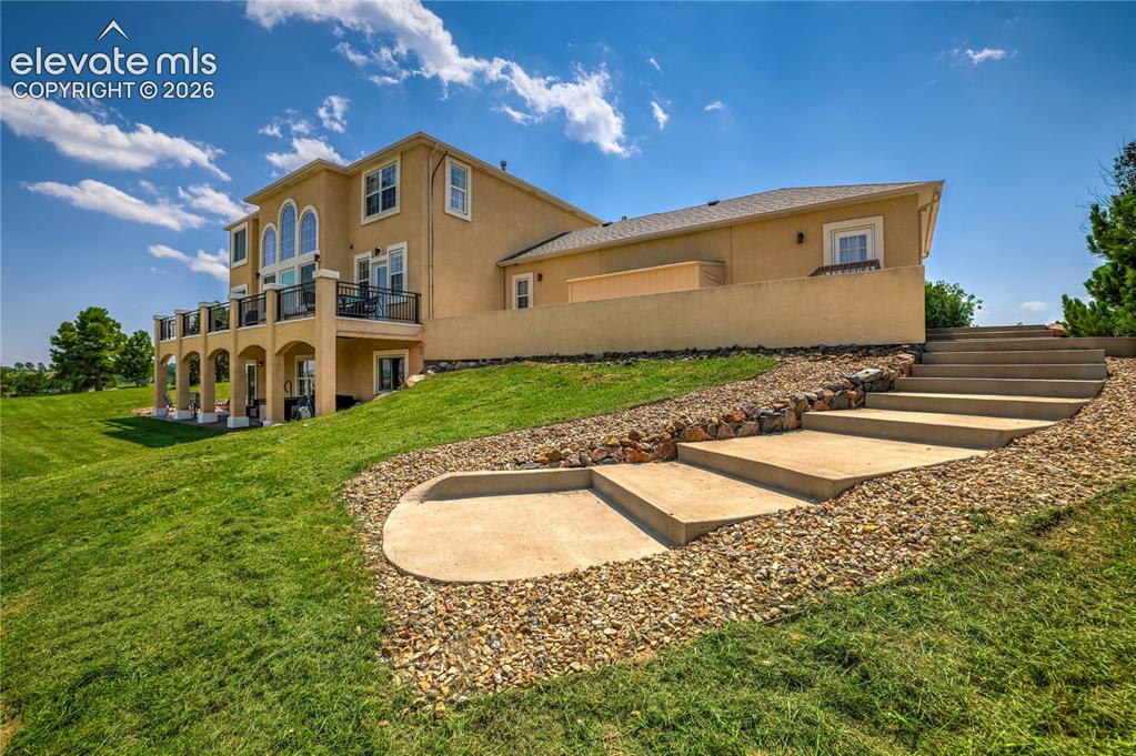 Image 7 of 49: Terraced concrete steps with gravel surround, leading to a stucco exterior 