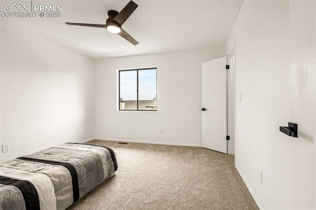 Image 12 of 27: Carpeted bedroom with a textured ceiling and a ceiling fan