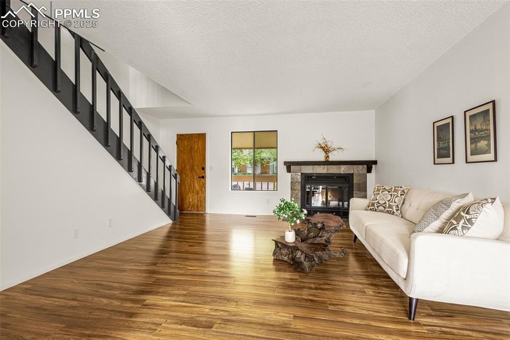 Image 2 of 27: Living room featuring stairway, wood finished floors, a textured ceiling, a