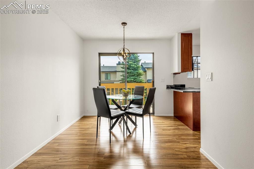 Image 3 of 27: Dining space featuring wood finished floors, a chandelier, a textured ceili