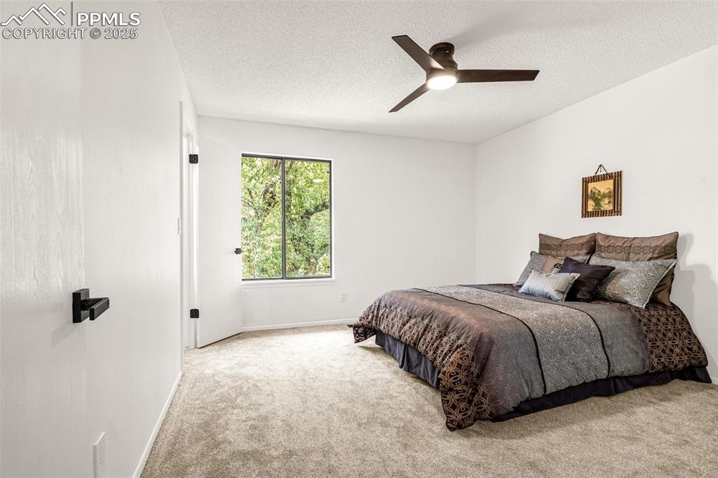 Image 8 of 27: Bedroom with carpet flooring, a textured ceiling, and ceiling fan