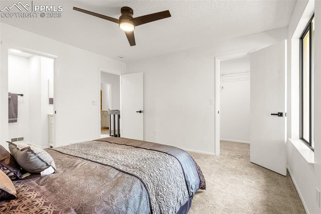Image 9 of 27: Bedroom featuring light colored carpet, a spacious closet, a textured ceili