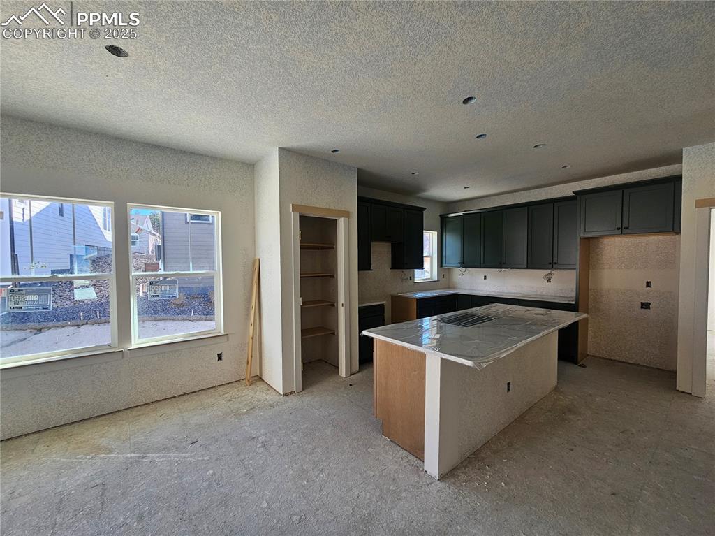 Image 2 of 9: Kitchen with a center island, a kitchen bar, and a textured ceiling