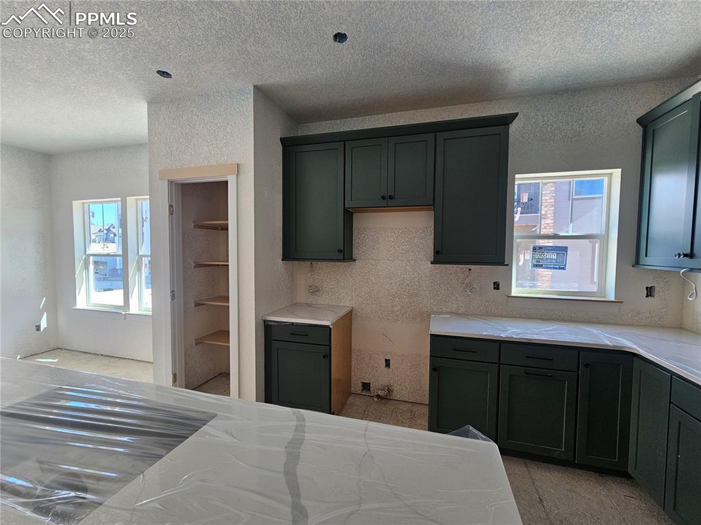 Image 4 of 9: Kitchen featuring light stone countertops, a textured ceiling, and a textur
