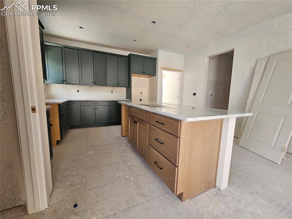 Image 8 of 9: Kitchen with a center island and light stone counters