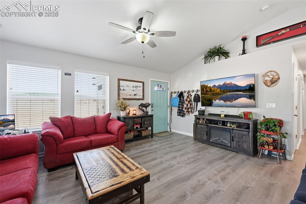 Image 10 of 28: Vaulted ceiling living area featuring wood-finish flooring, two large windo