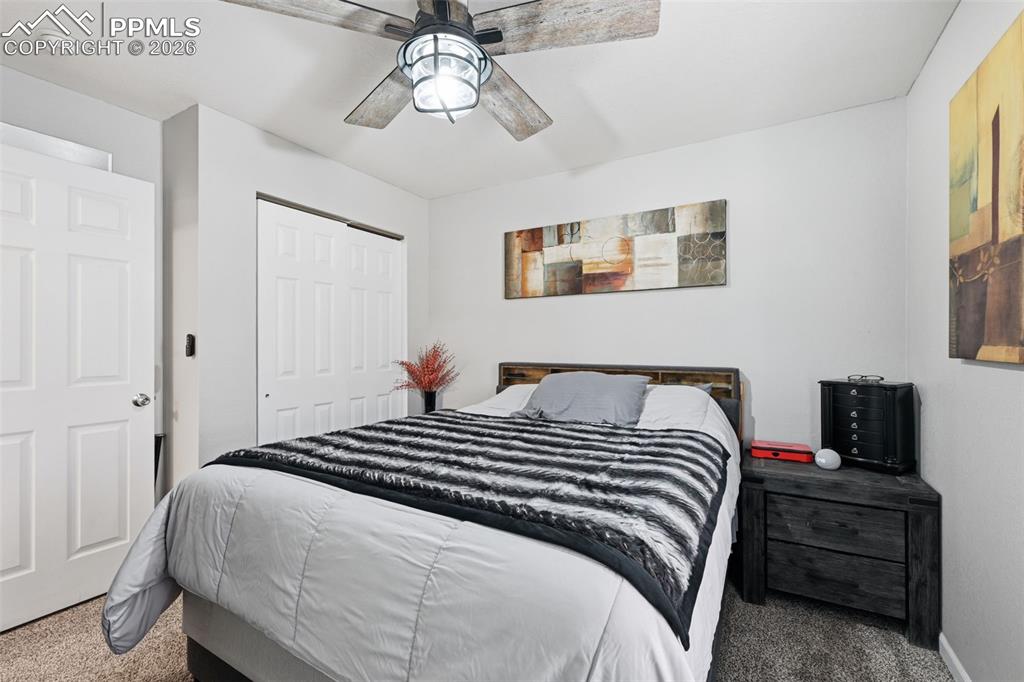 Image 11 of 28: Bedroom featuring neutral-toned carpeting, a paneled door, bi-fold closet d