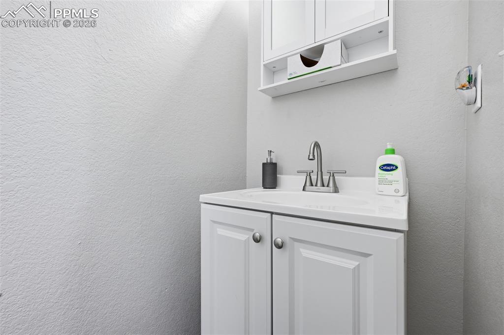 Image 16 of 28: White vanity with paneled doors, brushed nickel hardware, and an integrated