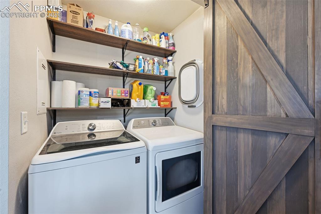 Image 19 of 28: Dedicated laundry area featuring a wood-finish barn door, two levels of ope