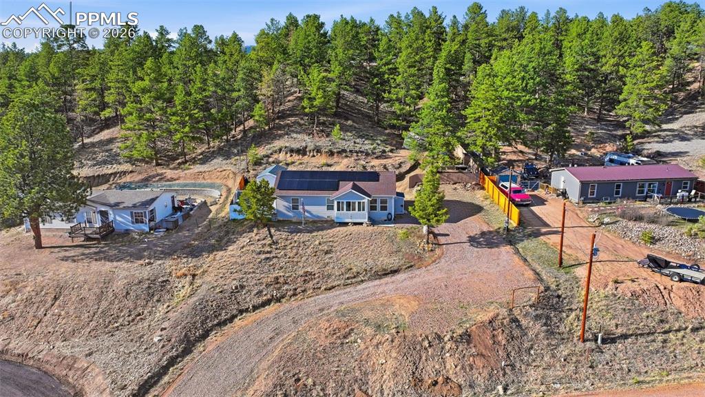 Image 2 of 28: Multiple residences situated on a sloped, tree-lined property featuring a g