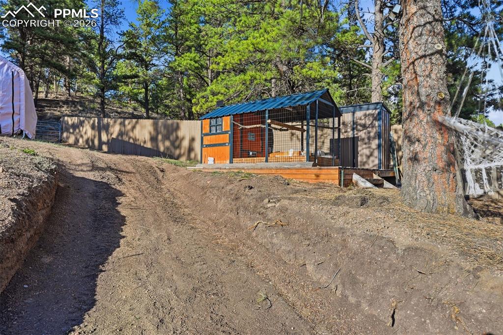 Image 20 of 28: Outbuilding featuring a wood-finish exterior, covered run, and an elevated 