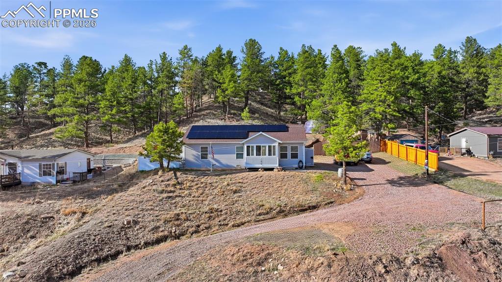 Image 26 of 28: Hillside residence with light blue siding and a brown roof