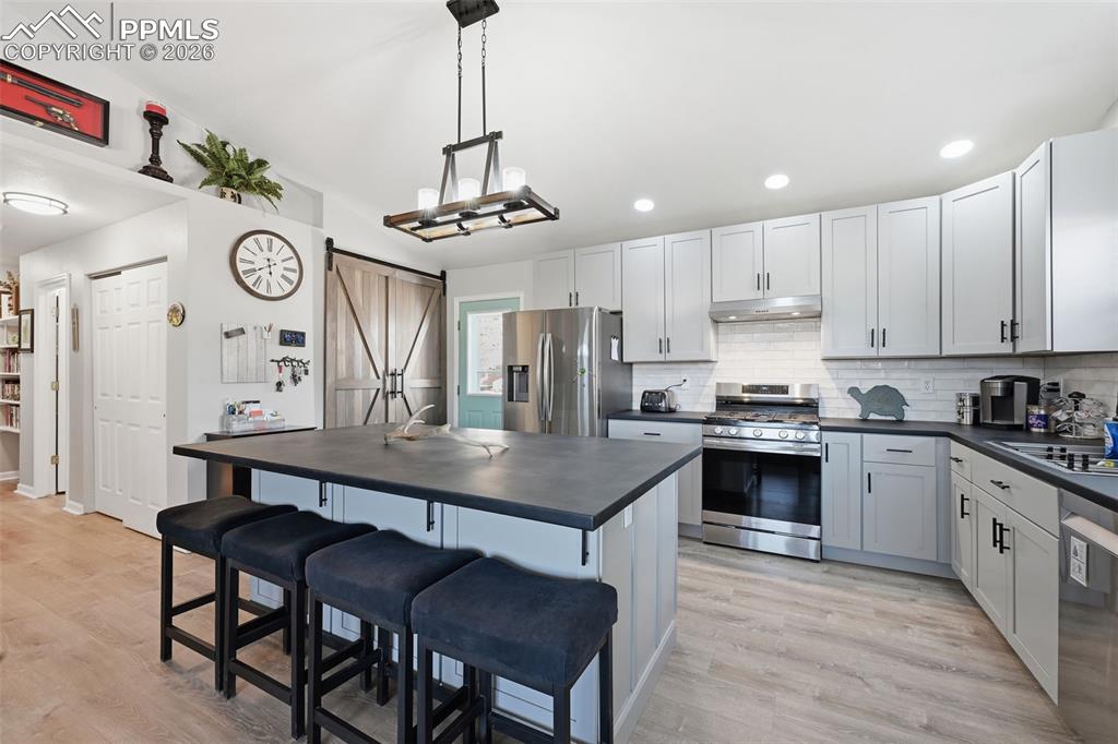 Image 4 of 28: Open-concept kitchen featuring light-toned cabinetry, a spacious central is