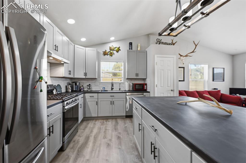 Image 5 of 28: Open-concept kitchen featuring light gray cabinetry, stainless steel applia