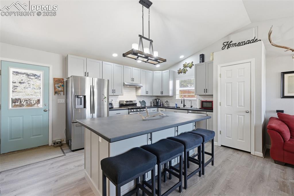 Image 6 of 28: Kitchen featuring an island with seating, stainless steel appliances, light