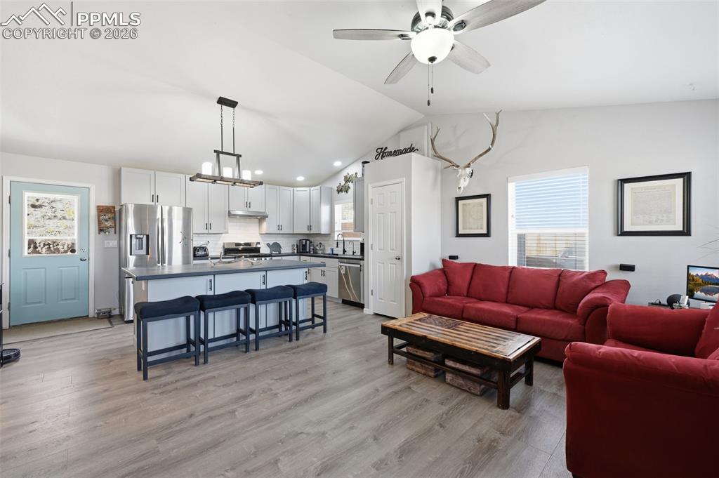 Image 8 of 28: Open-concept living space featuring a vaulted ceiling and wood-finish floor