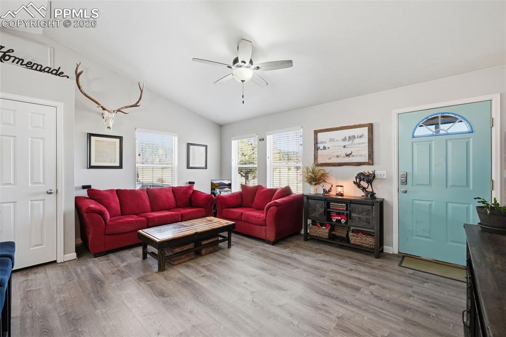 Image 9 of 28: Living area featuring vaulted ceilings, wood-finish flooring, a ceiling fan