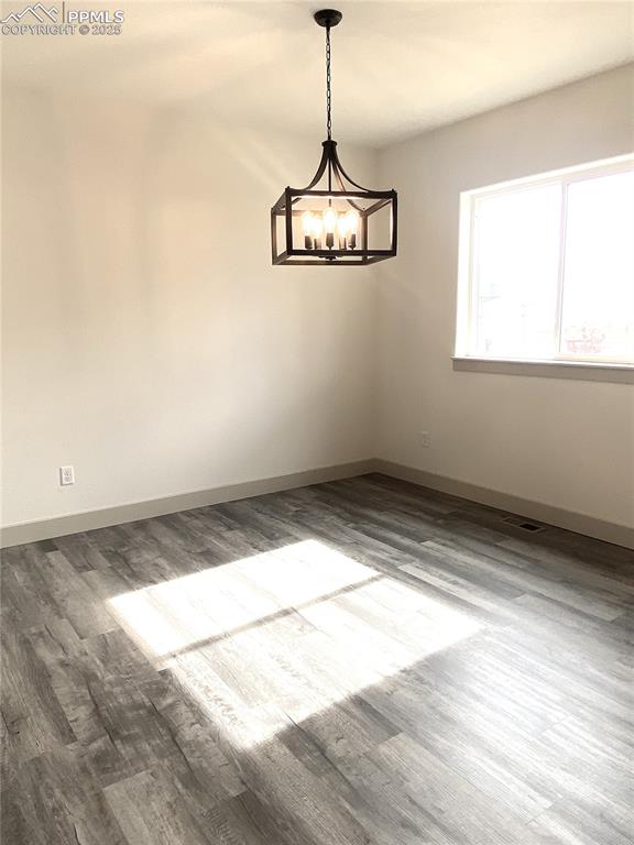 Image 10 of 35: Unfurnished room with wood finished floors and a chandelier