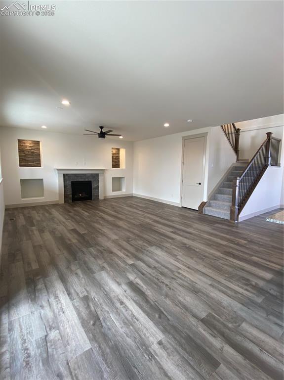 Image 13 of 35: Unfurnished living room with stairway, dark wood-style floors, a fireplace,