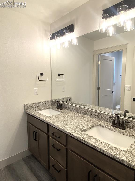 Image 27 of 35: Full bath featuring double vanity, dark wood-type flooring, and a textured 