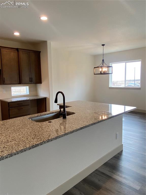 Image 6 of 35: Kitchen with light stone counters, recessed lighting, dark wood finished fl