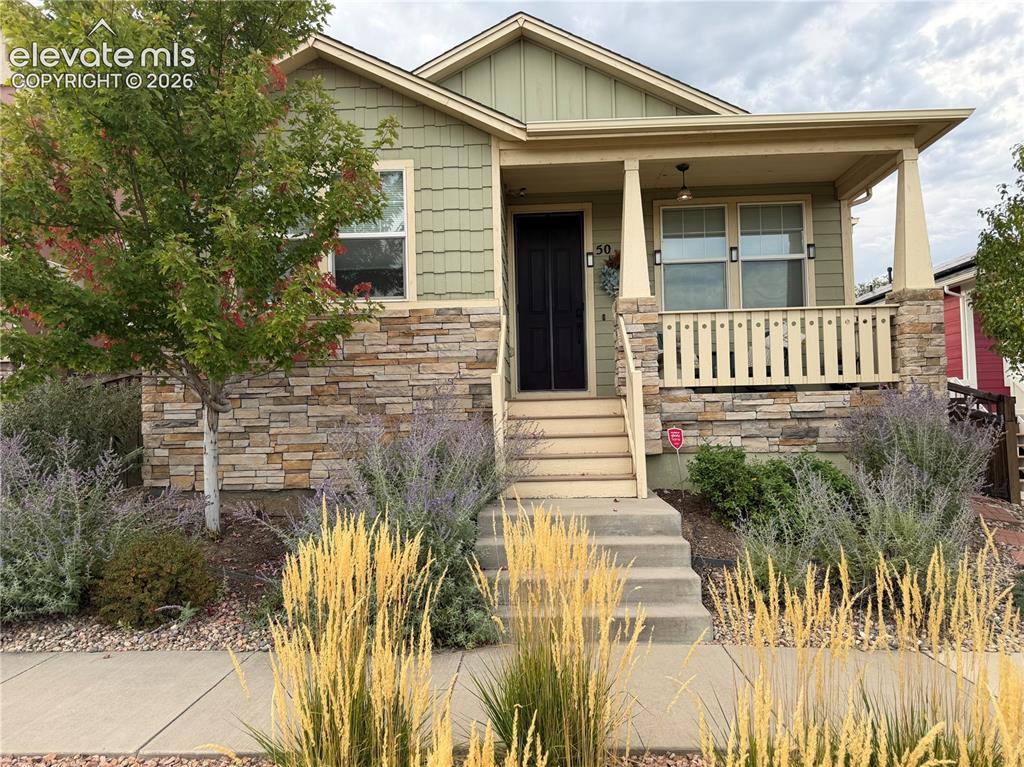Caption: Exterior featuring stone veneer accents, covered front porch, and mature landscaping