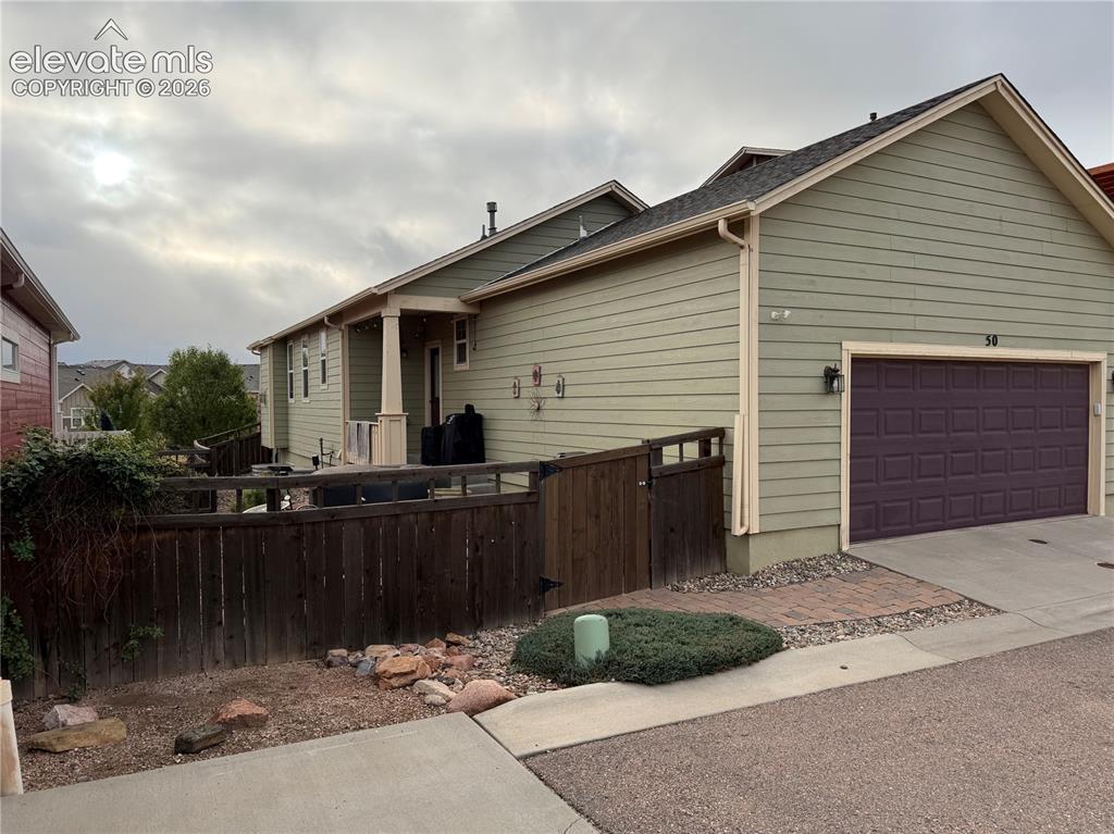 Image 4 of 6: Exterior featuring horizontal siding, dark paneled garage door, covered por