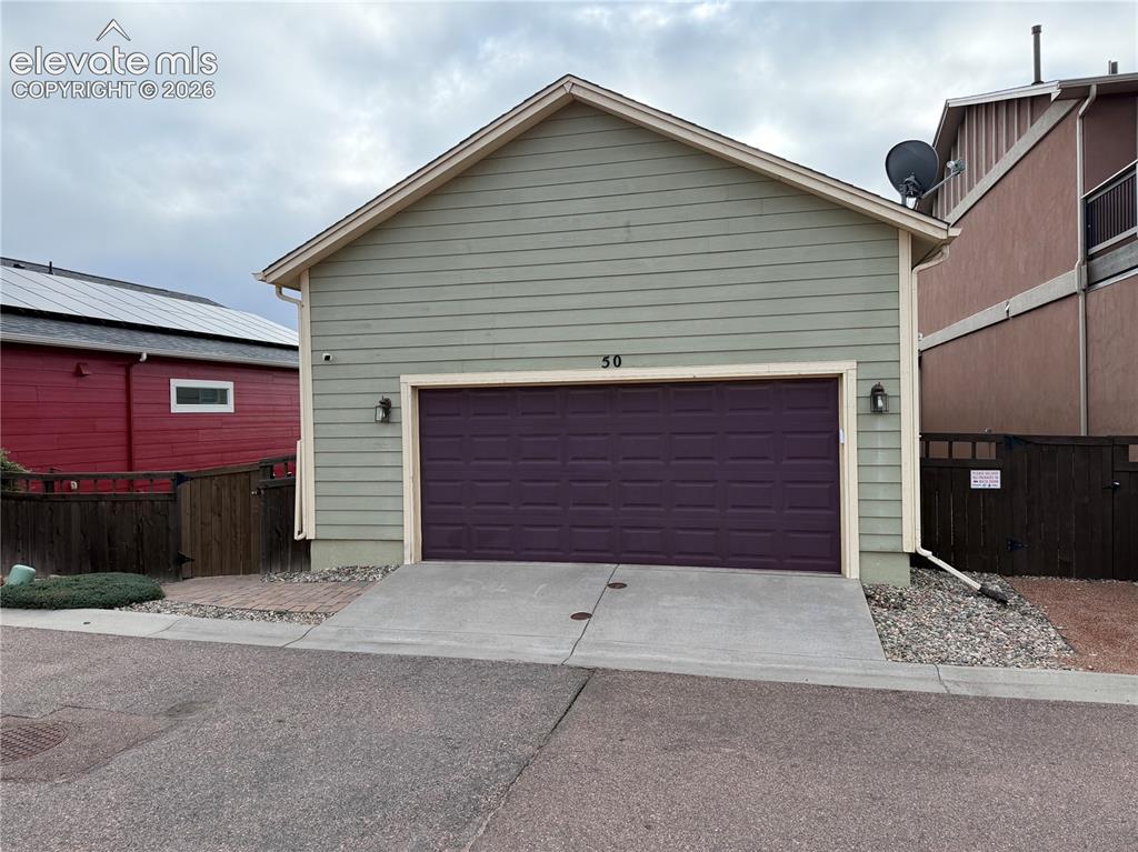 Image 6 of 6: Attached garage with a purple paneled door, horizontal siding, and exterior