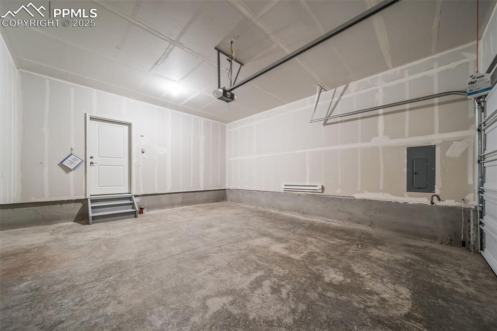 Image 24 of 25: Garage with electric panel and a garage door opener