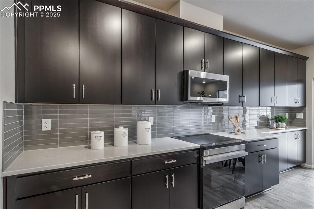 Image 4 of 25: Kitchen featuring stainless steel appliances, decorative backsplash, light 