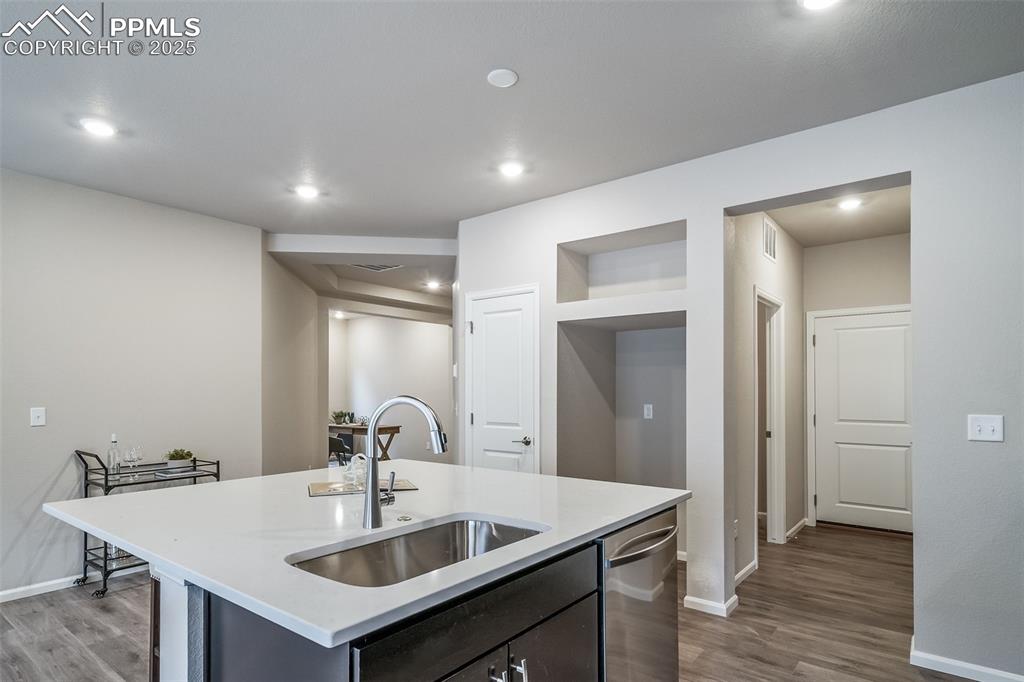 Image 5 of 25: Kitchen with dark wood-style flooring, light stone counters, a center islan