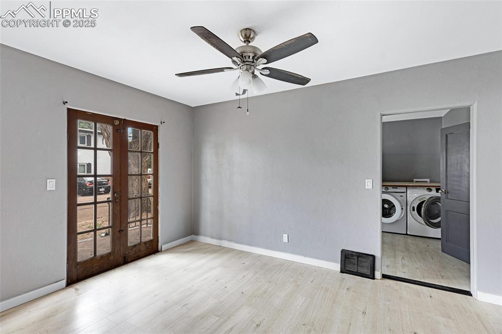 Image 6 of 16: Spare room with washer and dryer, french doors, a ceiling fan, and wood fin