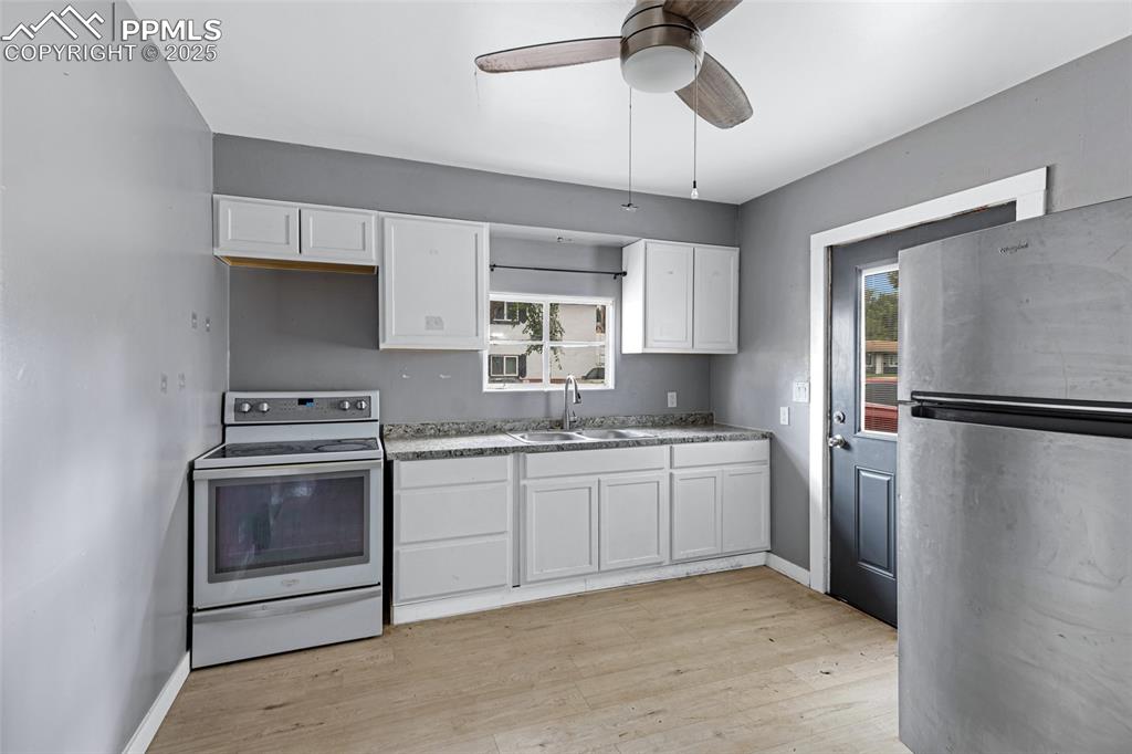 Image 9 of 16: Kitchen with freestanding refrigerator, white electric stove, white cabinet