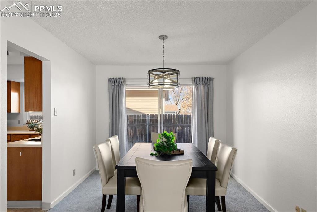 Image 4 of 16: Carpeted dining room featuring a notable chandelier, baseboards, and a text