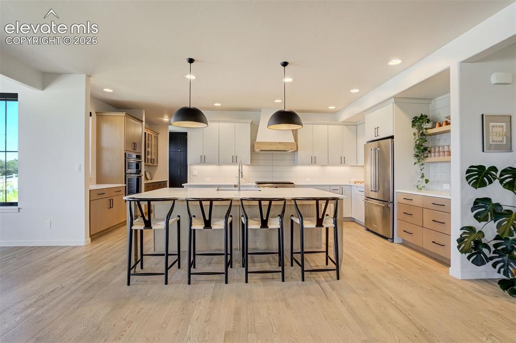 Image 10 of 50: Spacious kitchen featuring a large central island with seating, pendant lig