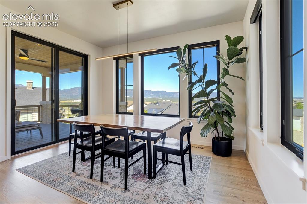 Image 19 of 50: Dining area featuring wood-finish flooring, a linear pendant light fixture,