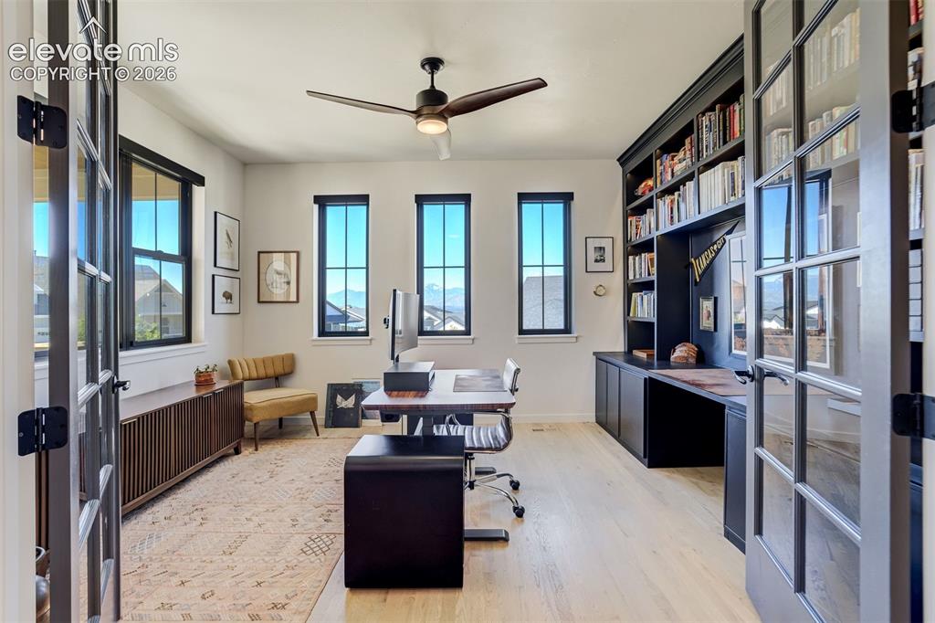 Image 20 of 50: Light wood-finish flooring with multiple windows featuring dark trim