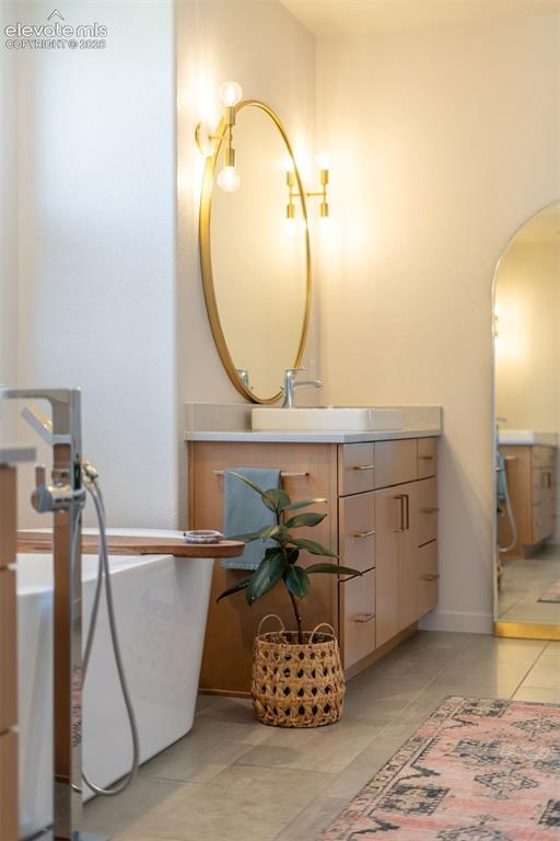Image 27 of 50: Freestanding soaking tub with floor-mounted faucet, wood-finish vanity with
