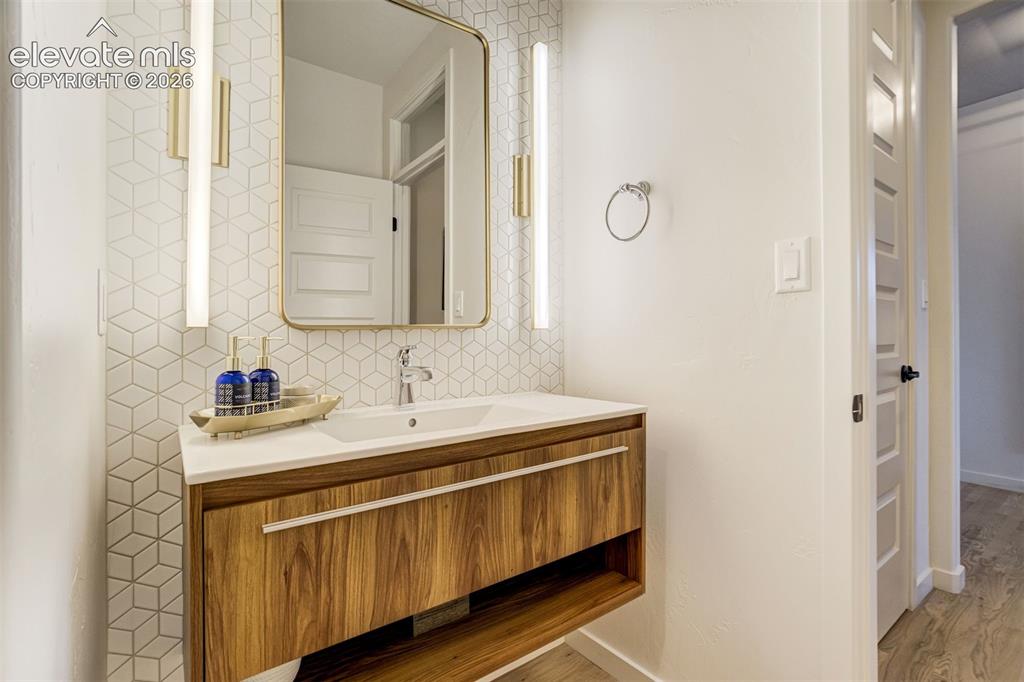 Image 32 of 50: Contemporary vanity featuring wood-finish cabinetry, white countertop, and