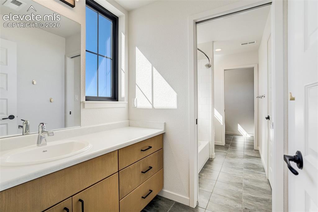 Image 36 of 50: Bathroom vanity with light wood-finish cabinetry, a white countertop, and a